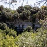 ...circondato da alte pareti rocciose nelle quali si intravedono le entrate di alcune grotte